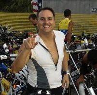 A man in white shirt and black shorts standing next to bicycles.