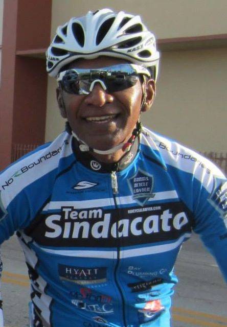 A man in blue and white shirt riding bicycle.