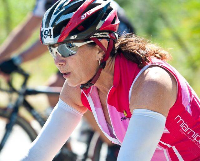 A woman in pink shirt and helmet on bike.
