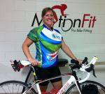 A woman standing next to her bicycle in front of motion fit.